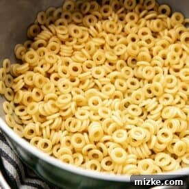Uncooked O-shaped pasta visibly dry and resting inside a large metal pot, ready for boiling.
