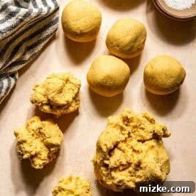 Gooey Cheese Pupusas 7 Balls and clumps of yellow corn dough are arranged on a light surface, with a bowl of oil, a bowl of salt, and a striped cloth nearby.