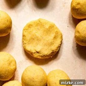 Gooey Cheese Pupusas 10 Eight round balls of dough surround a single flattened disc of dough on a light-colored surface.