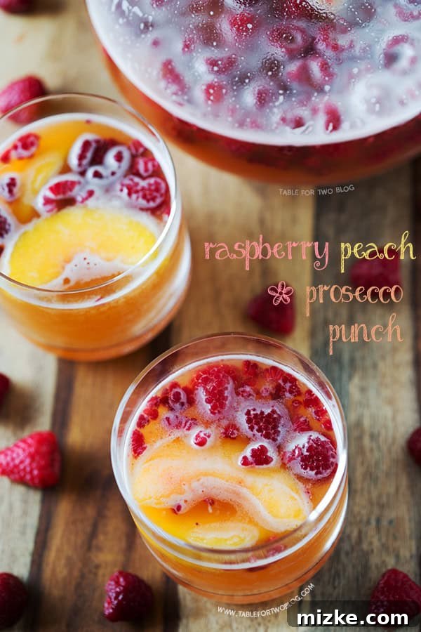 Refreshing Raspberry Peach Prosecco Punch for Your Next Celebration Vibrant Raspberry Peach Prosecco Punch in a clear glass pitcher, garnished with fresh raspberries and peach slices, ready for serving.