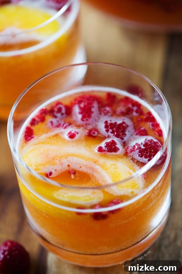 Easy-to-Make Raspberry Peach Prosecco Punch for Parties An elegant serving of Raspberry Peach Prosecco Punch in a stemmed glass, set against a bright background, perfect for a party.
