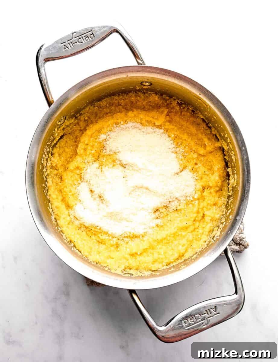 These polenta fries are made from cheesy polenta cut into strips, brushed with olive oil, and baked to crispy golden brown. Adding parmesan cheese to cooked polenta in a pot.