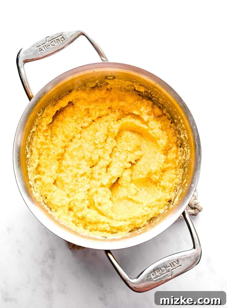 These polenta fries are made from cheesy polenta cut into strips, brushed with olive oil, and baked to crispy golden brown. Cooked polenta in a pot after adding parmesan.