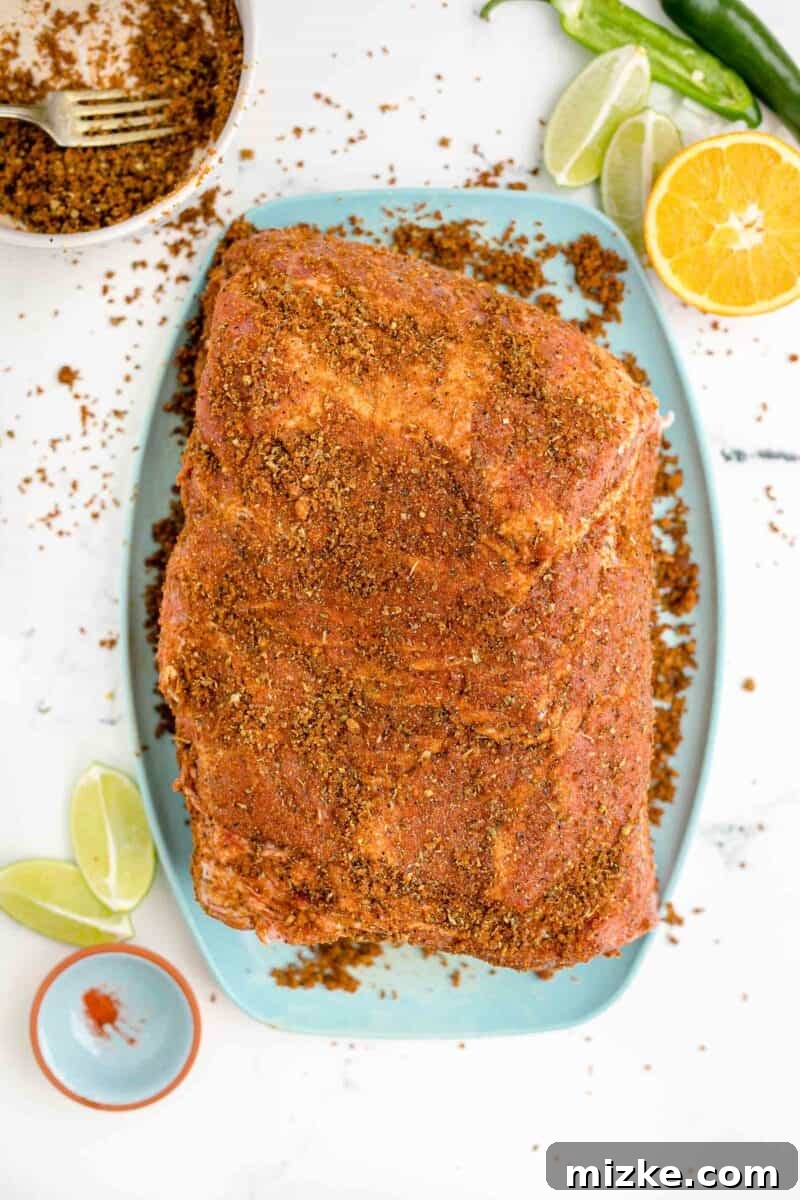 Melt-Away Slow Cooker Pork Carnitas 7 The pork has been generously seasoned with a spice rub and is now resting on a blue cutting board.