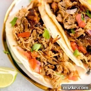 Two tacos are beautifully garnished and plated next to fresh limes and oranges, showcasing the vibrant colors of the dish.