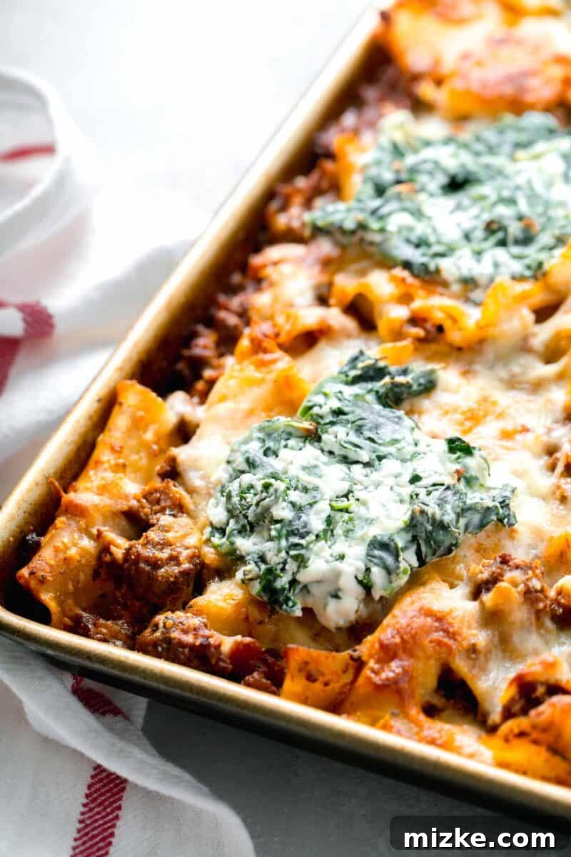 Effortless Sheet Pan Lasagna 2 baked sheet pan lasagna with dollop of spinach and ricotta mixture on top, fresh out of the oven