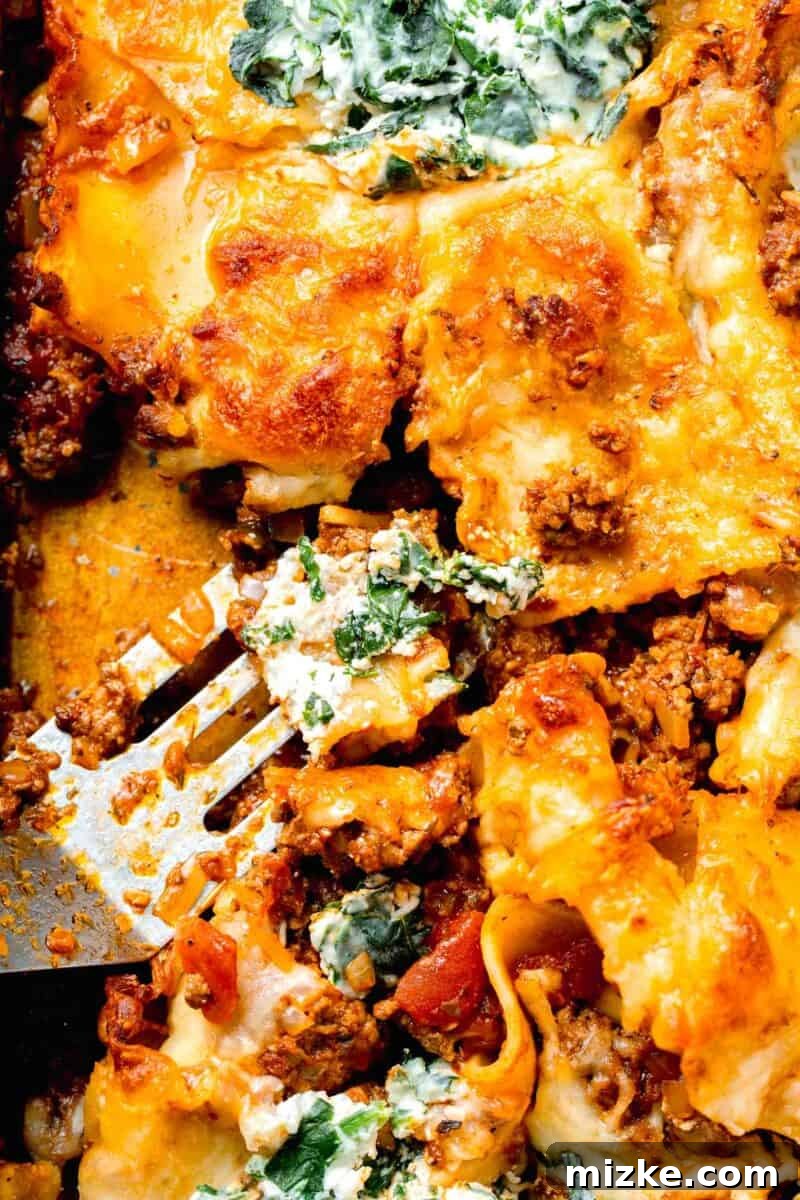 Effortless Sheet Pan Lasagna 13 sheet pan lasagna with a piece scooped out from a metal spatula, showing the layers