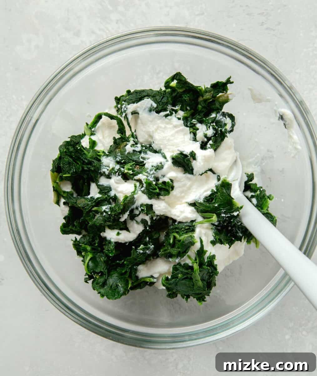 Effortless Sheet Pan Lasagna 4 ricotta and spinach in a clear bowl with a silicone spoon