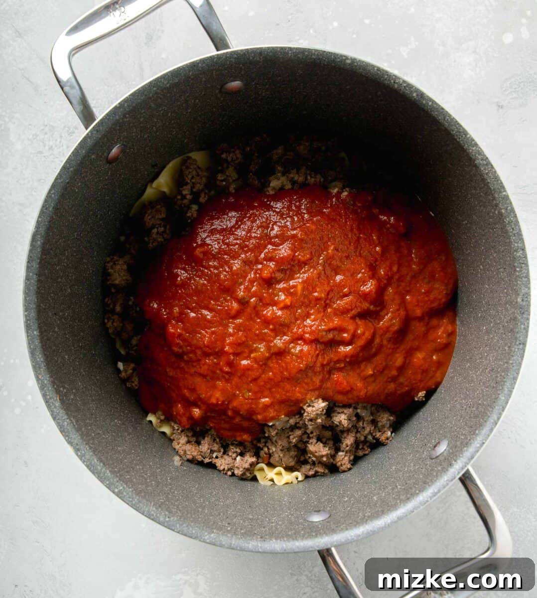 Effortless Sheet Pan Lasagna 8 marinara sauce on top of ground beef mixture and lasagna noodles in a large pot