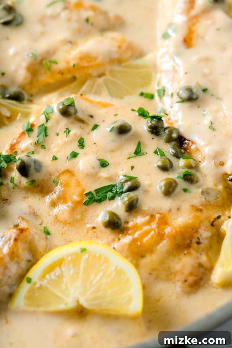 Velvety Lemon Chicken Piccata 3 Platter showcasing succulent chicken breasts drenched in a creamy lemon sauce, garnished with fresh parsley, briny capers, and a vibrant lemon wedge.
