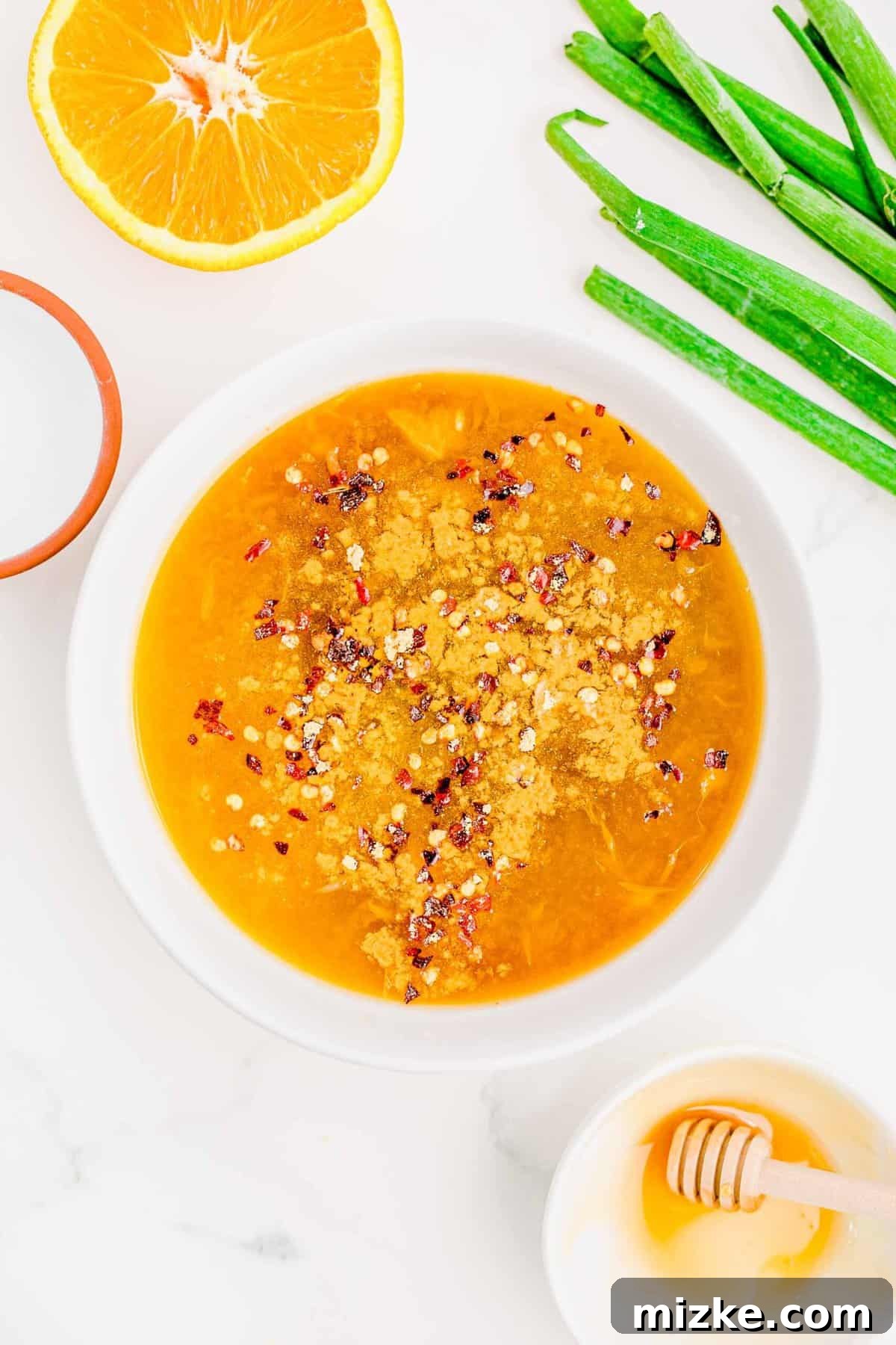 Combining all the vibrant flavors for the orange chicken sauce. Various sauce ingredients being whisked together in a bowl, preparing the orange chicken sauce.