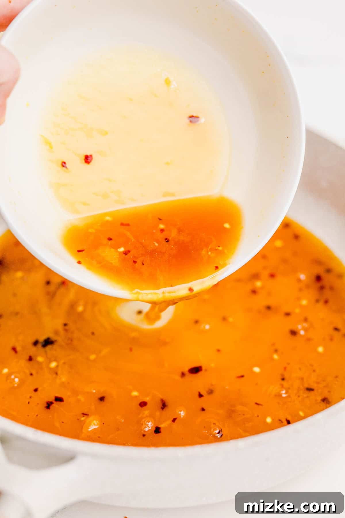 Beginning to cook the delectable orange chicken sauce in the skillet. Pouring the orange chicken sauce mixture into a hot skillet, ready for simmering.