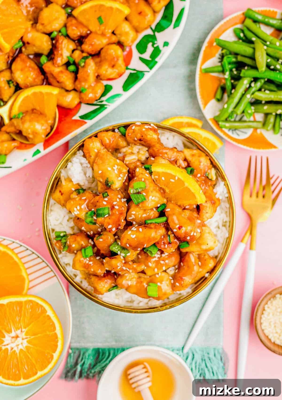 A complete and satisfying homemade orange chicken meal with delicious sides. A generous serving of orange chicken over white rice, accompanied by a side of vibrant green beans, ready to be enjoyed.