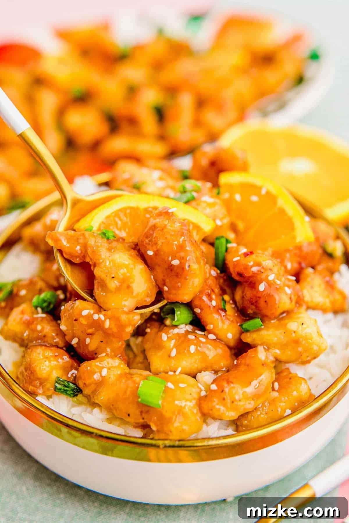 Enjoying the perfect bite of homemade orange chicken, featuring its signature crispy texture and irresistible sauce. A close-up shot of a person taking a bite of crispy orange chicken with a fork, showing the vibrant sauce and tender chicken.