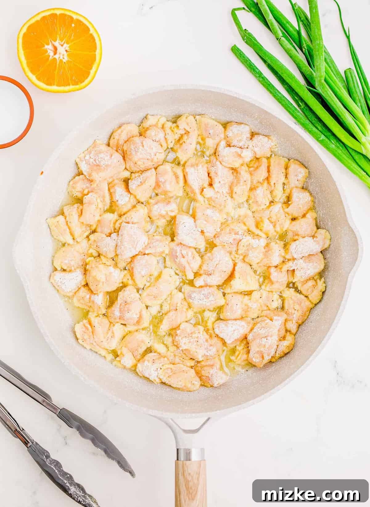 Frying chicken to a perfect golden-brown crisp. Several breaded chicken bites sizzling in hot oil in a cast-iron skillet.