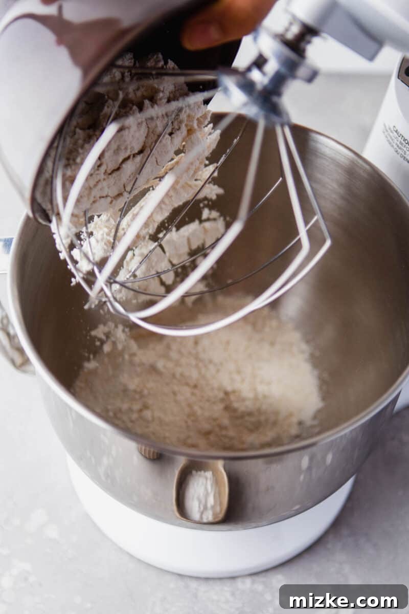 Perfectly Baked Vanilla Delights 4 Dry ingredients are being whisked together in a stand mixer, preparing the base for the donut batter.