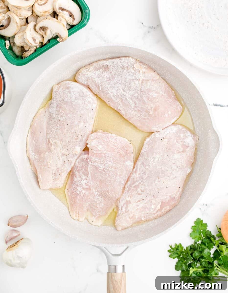 Simple Weeknight Chicken Marsala 6 Several flour-coated chicken breasts are placed into a hot skillet, ready to be seared to a beautiful golden brown.