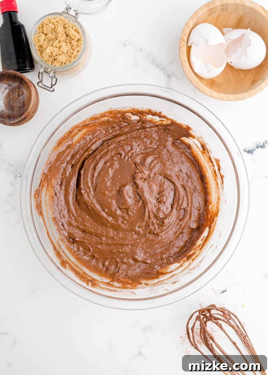 The fully mixed wet ingredients for the chocolate donut batter in a clear glass bowl, ready to be combined with the dry ingredients.