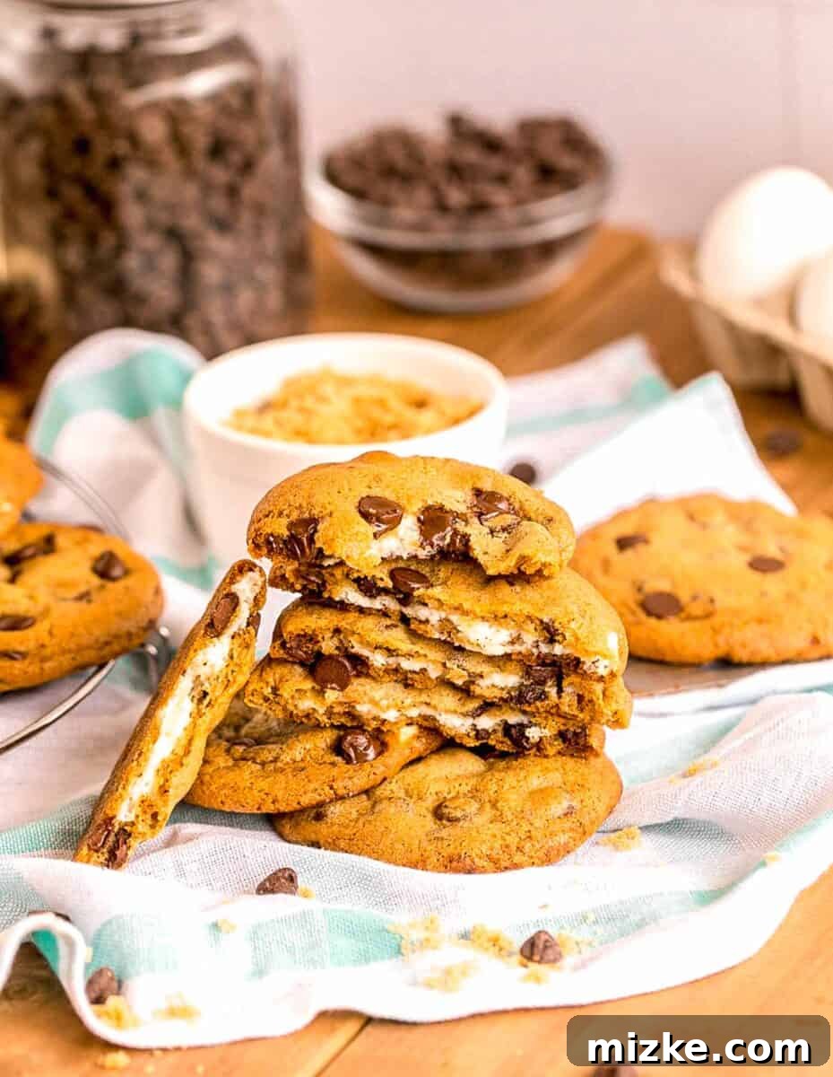 Decadent Cheesecake-Stuffed Chocolate Chip Cookies 11 several cheesecake stuffed chocolate chip cookies are placed on top of a tea towel, ready to be enjoyed.