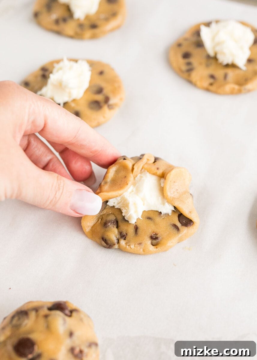 Decadent Cheesecake-Stuffed Chocolate Chip Cookies 9 cookie dough is being formed around a cheesecake center, sealing it inside.
