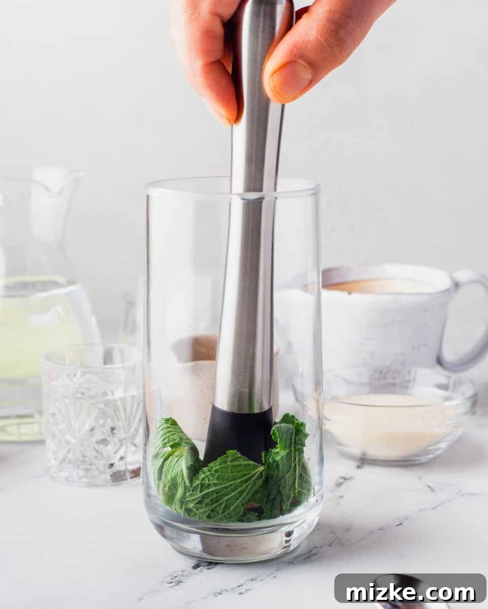 Sun-Kissed Mint Splash 4 Fresh mint leaves are gently muddled in the bottom of a cocktail glass, preparing for an Orange Mojito.