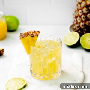 A Pineapple Paloma glass, surrounded by fresh lime slices, ready to be enjoyed.