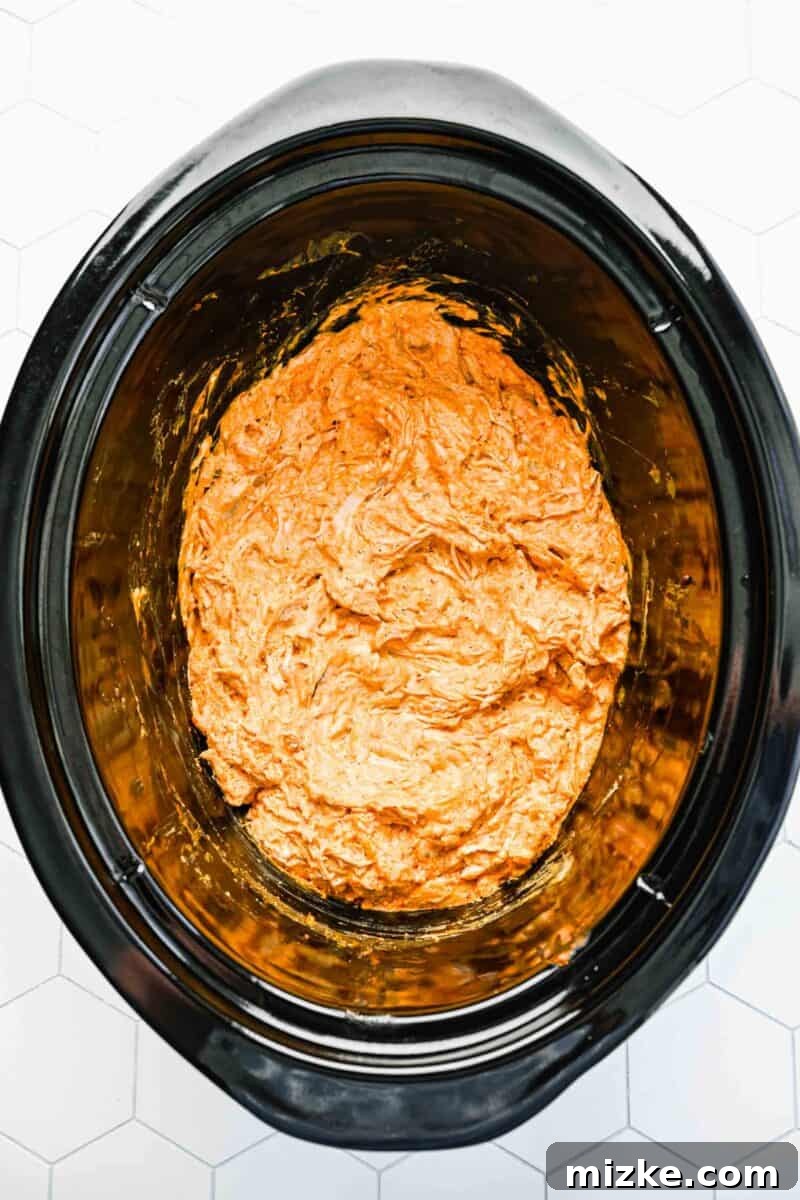 Creamy Slow Cooker Buffalo Chicken Dip 2 A serving of creamy buffalo chicken dip still in the slow cooker, ready to be scooped, showing its warm and inviting texture.