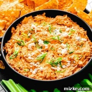 Creamy Slow Cooker Buffalo Chicken Dip 3 Buffalo chicken dip in a serving bowl near celery sticks and tortilla chips.