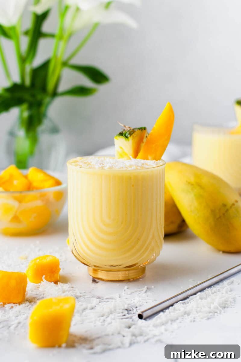 Velvet Mango Sunset 2 A vibrant Mango Colada cocktail garnished with fresh fruits, set against a tropical backdrop.