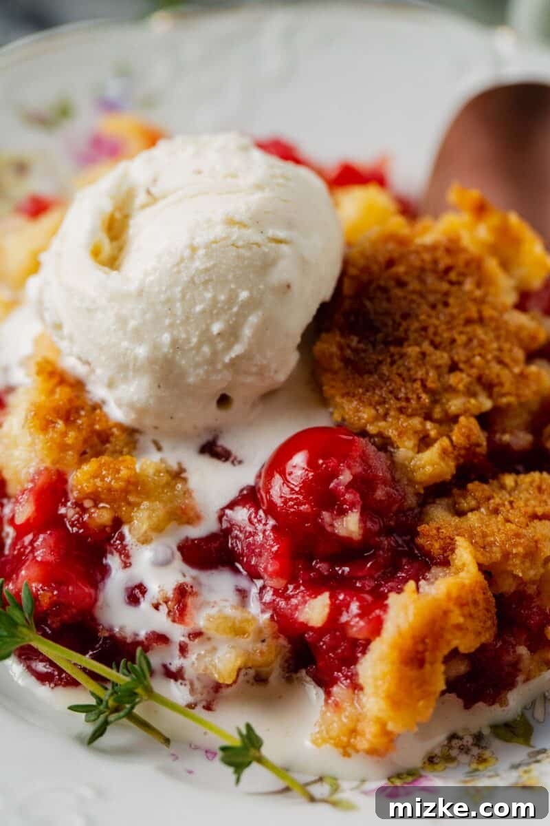 Effortless Cherry Delight 9 A close-up view of cherry dump cake on a plate with melted vanilla ice cream, highlighting the sweet cherries and buttery topping.
