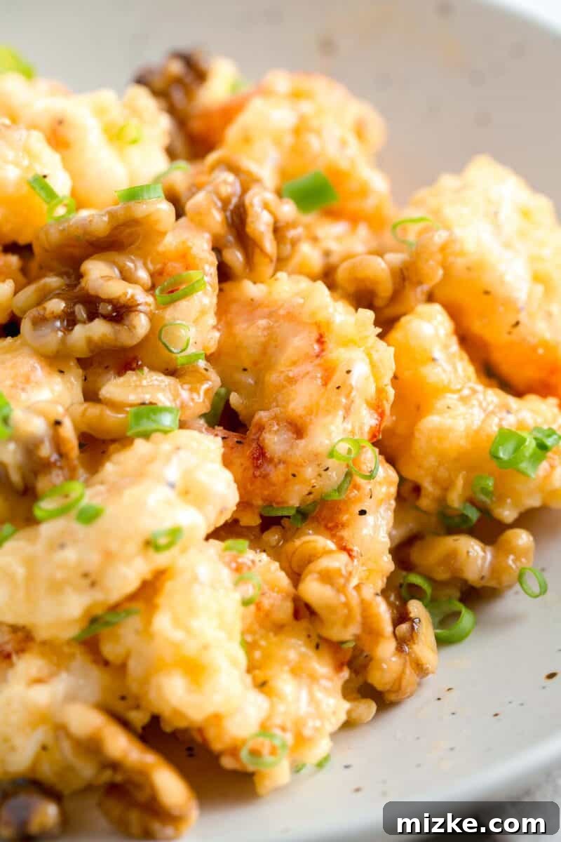 Crispy Honey Walnut Shrimp 3 Honey walnut shrimp with fresh scallions and walnuts on top, served in a white bowl.
