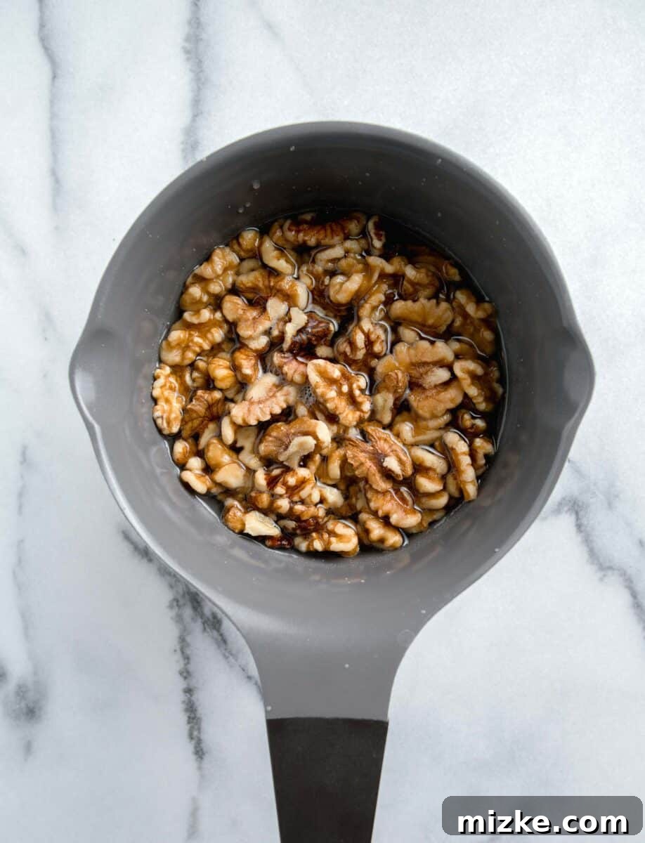 Crispy Honey Walnut Shrimp 5 Walnuts simmering in a grey nonstick pot with sugar and water, preparing to be candied.