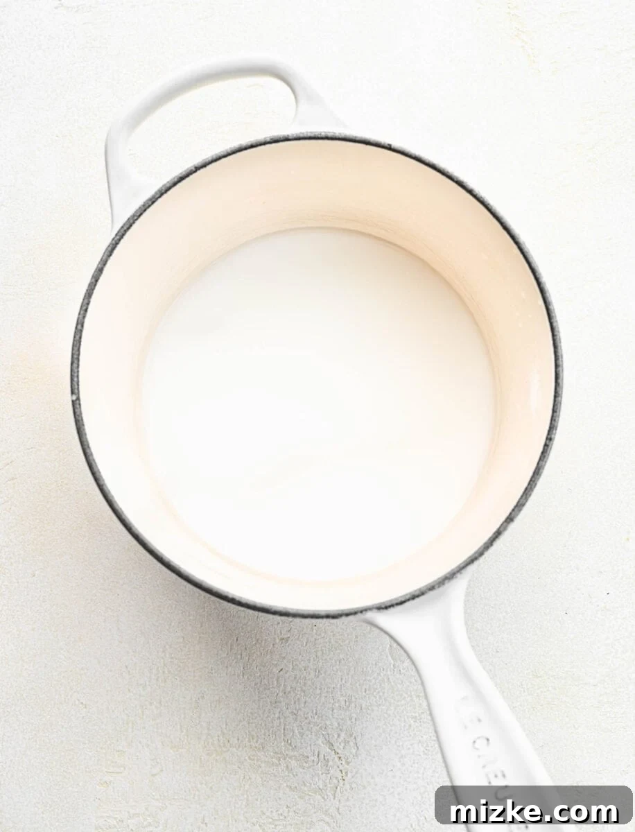 Preparing the base: water and cornstarch are whisked until smooth in a pot, a crucial step for a thick strawberry cake filling. Water and cornstarch being whisked together in a small pot on the stovetop to form a smooth slurry.