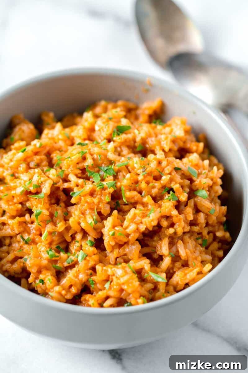 instant pot mexican rice with fresh parsley sprinkled top in a bowl next to two spoons