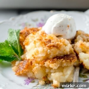 A delicious pineapple dump cake on a floral dessert plate, ready to be served with a spoon and ice cream.