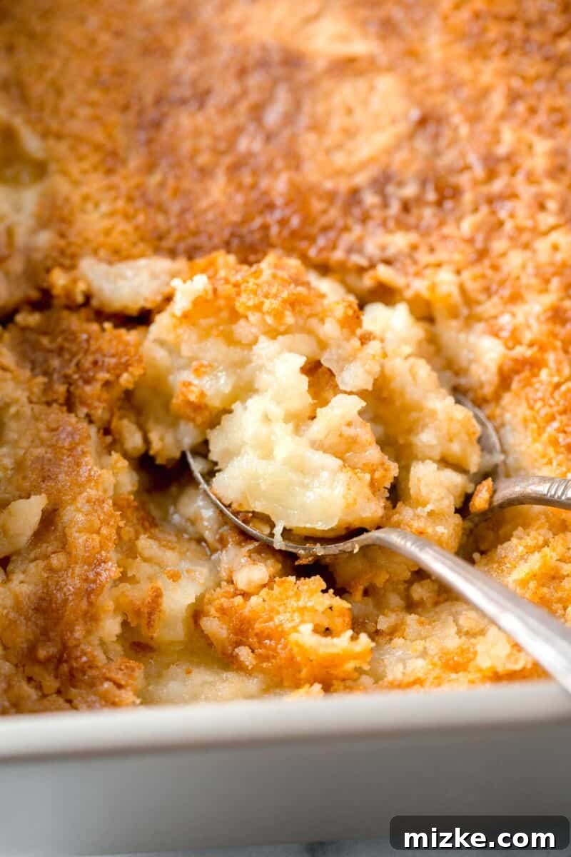 Two spoons dug into a freshly baked pineapple dump cake, showing its moist and crumbly texture.