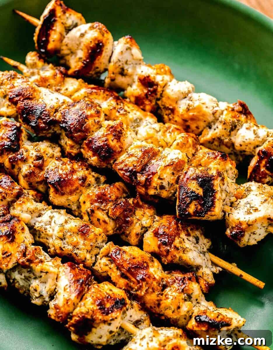 Grilled Greek chicken souvlaki skewers on a green platter