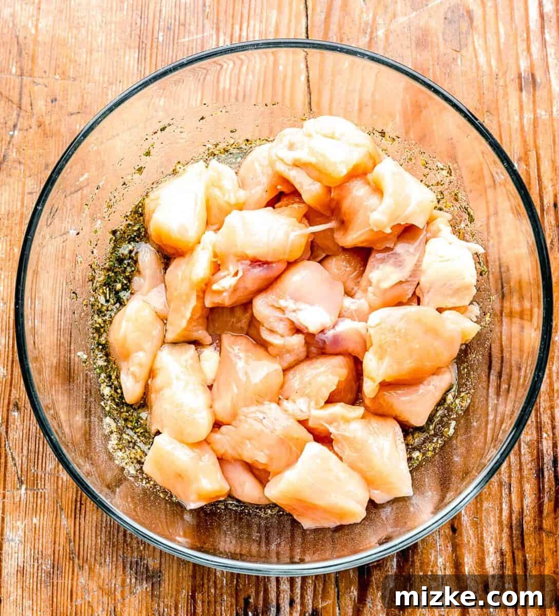 Raw chicken added to the Greek seasoning in the clear bowl