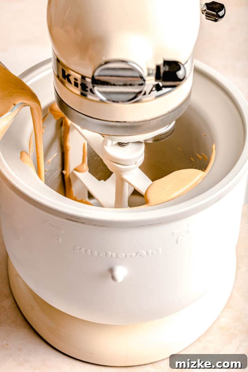 Espresso Chocolate Chip Bliss 6 The homogenous espresso ice cream mixture being carefully poured into the frozen bowl of a KitchenAid stand mixer ice cream attachment, ready for churning.
