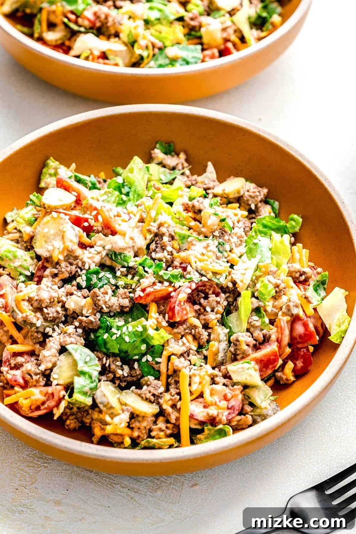 Big Mac salad is made up of cooked ground beef tossed together with crispy lettuce and tomatoes in a creamy, thousand islands-esque dressing. Big Mac salad served in 2 bowls.