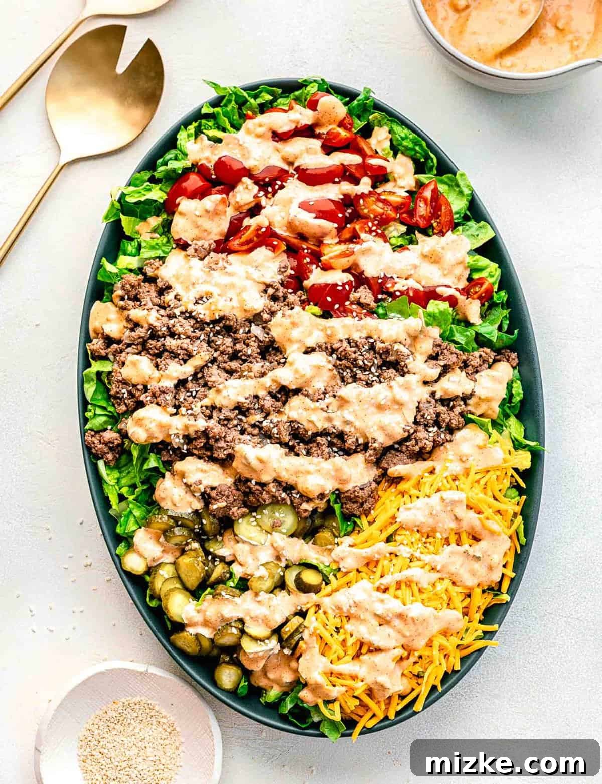 Big Mac salad is made up of cooked ground beef tossed together with crispy lettuce and tomatoes in a creamy, thousand islands-esque dressing. Big Mac salad on a serving platter before being tossed.