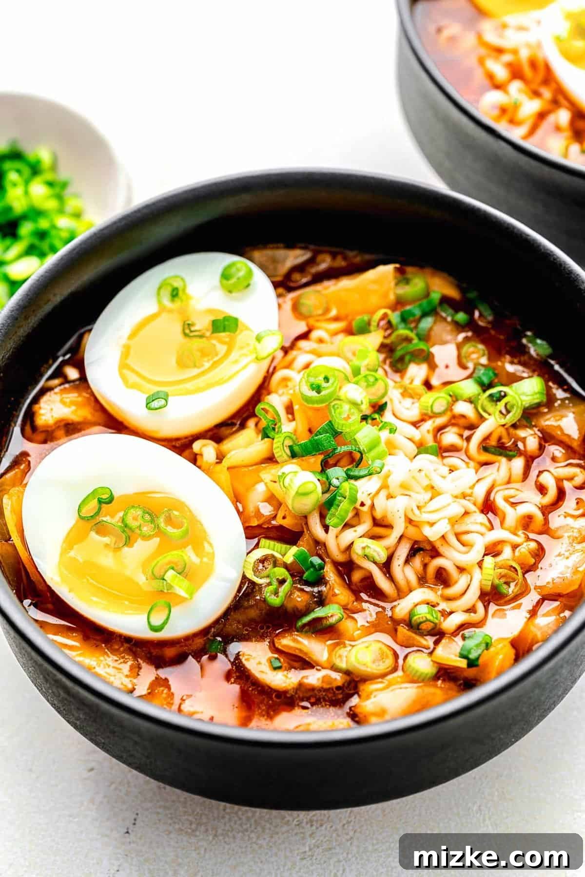 Kimchi Ramen: Tender Noodles & Flavorful Broth with Kimchi and Mushrooms A steaming bowl of homemade kimchi ramen, garnished with a soft-boiled egg, green onions, and fresh kimchi chunks.