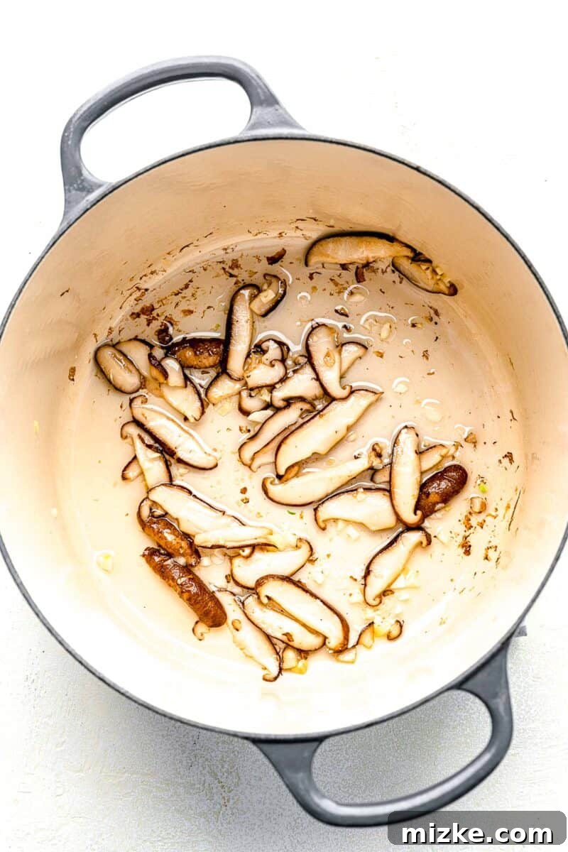 Starting the Kimchi Ramen: Sautéing Mushrooms and Garlic Sautéing sliced shiitake mushrooms and minced garlic in a small pot over medium heat.