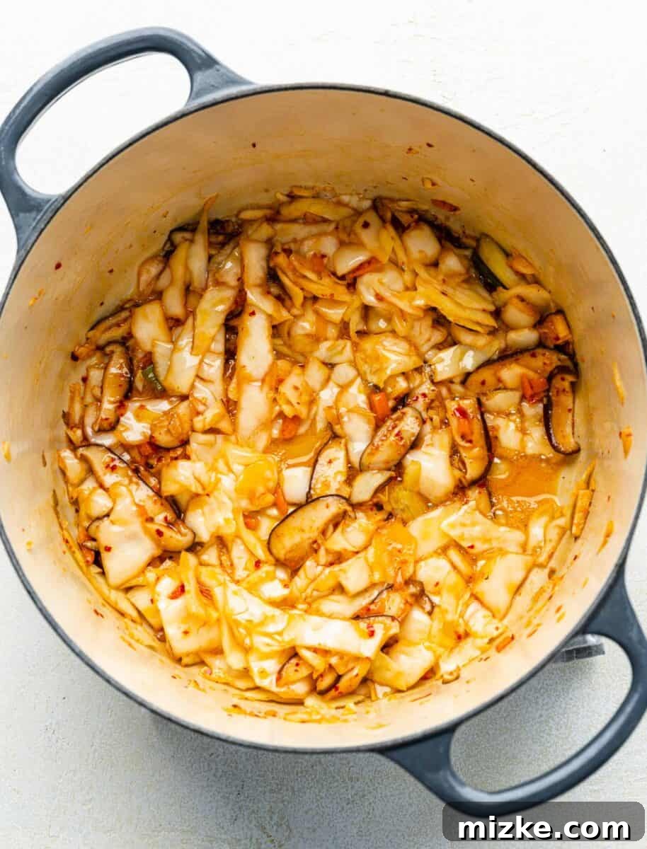 Infusing Flavor: Sautéing Kimchi with Mushrooms and Garlic Sautéed mushrooms, fresh kimchi, and minced garlic simmering together in a soup pot, building a flavorful base.