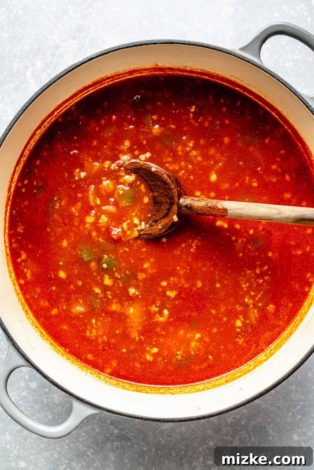 One-Pot Lasagna Soup 7 tomato liquid added to a large dutch oven with a wooden spoon