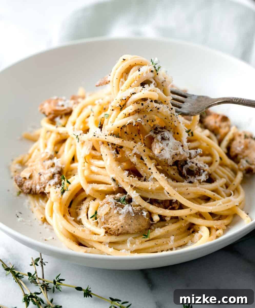 Velvety Lion's Mane Mushroom Pasta 8 creamy lions mane pasta being lifted out of a white bowl with a metal fork