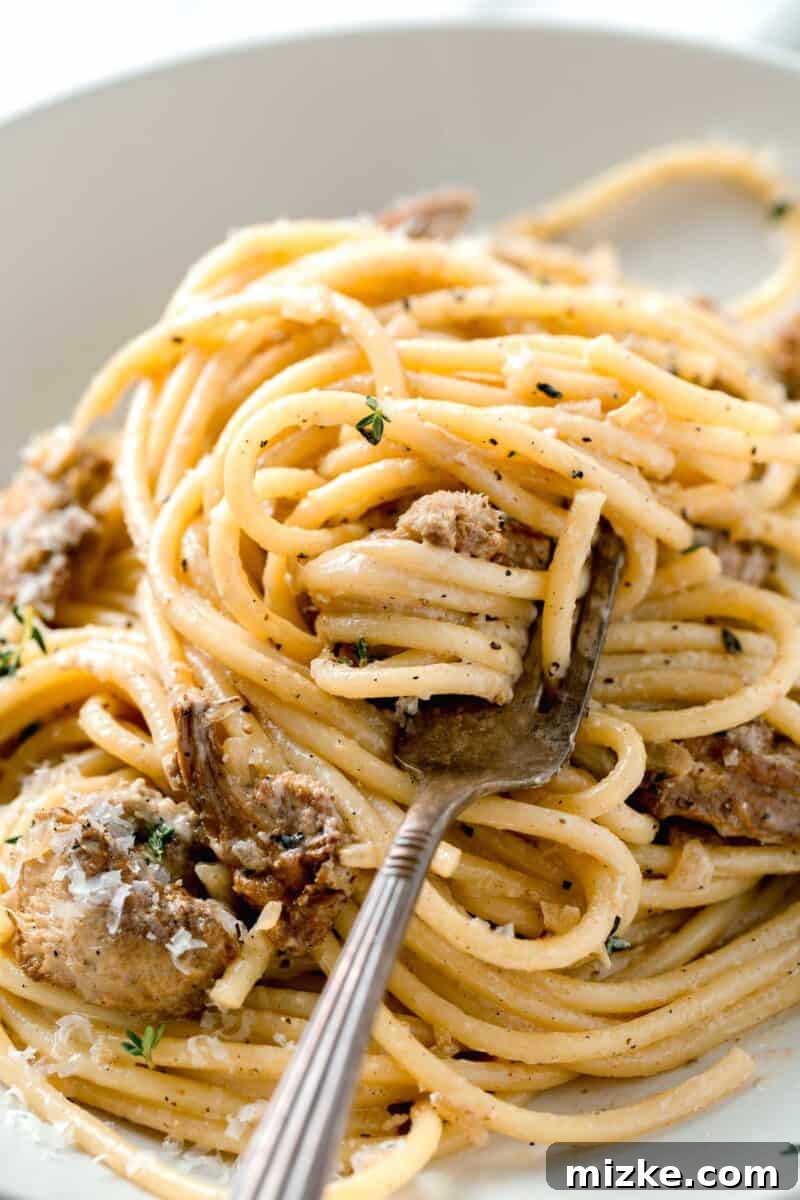 Velvety Lion's Mane Mushroom Pasta 9 creamy lions mane pasta twisted around a metal fork in a white bowl
