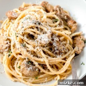 creamy lions mane pasta in a white bowl with a metal fork