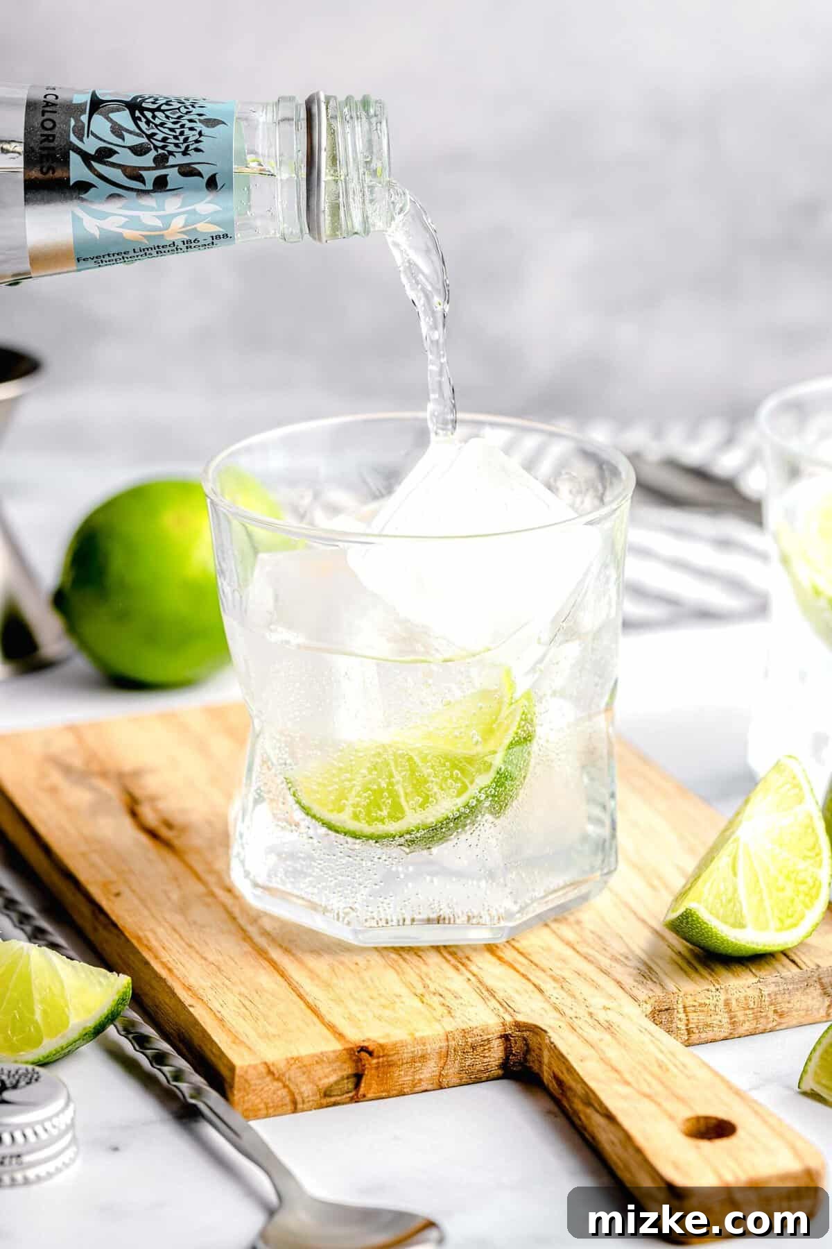 Watch as tonic water is poured over gin and ice to create this delicious, fizzy, botanical gin and tonic. Pouring tonic water into a glass with gin and ice, creating a gin and tonic.