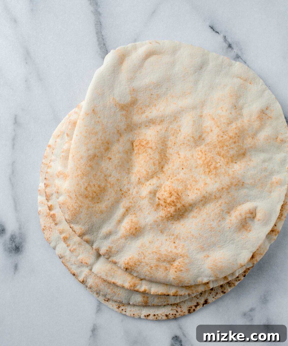 Crispy Air Fryer Pita Chips 3 Fresh pita bread rounds resting on a sleek marble countertop, ready for slicing into crispy air fryer pita chips.